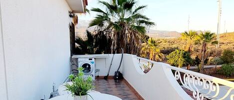A patio with a round table and chairs, a washing machine, and a potted plant.
