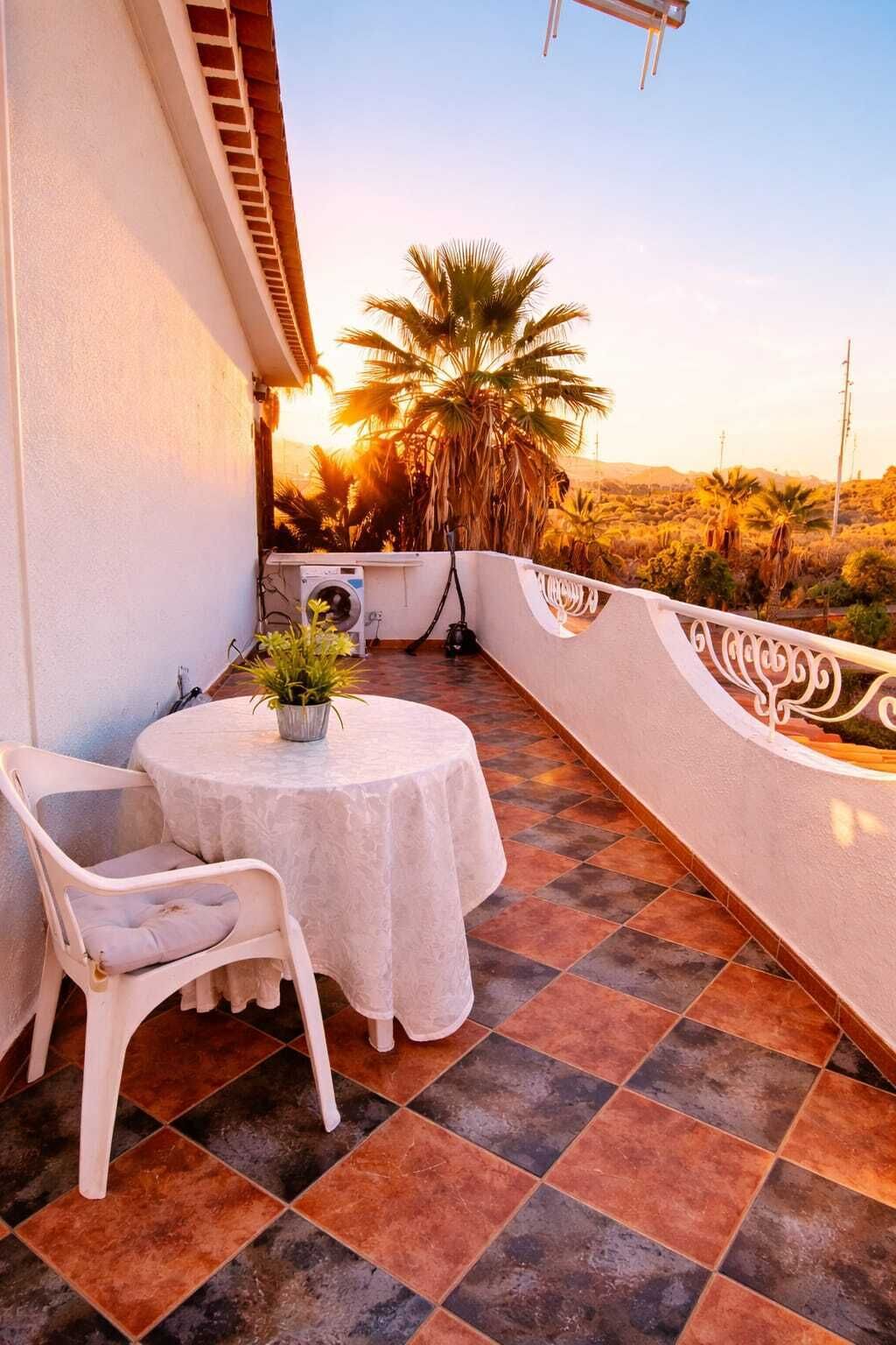 A balcony with a round table, a chair, and a potted plant.