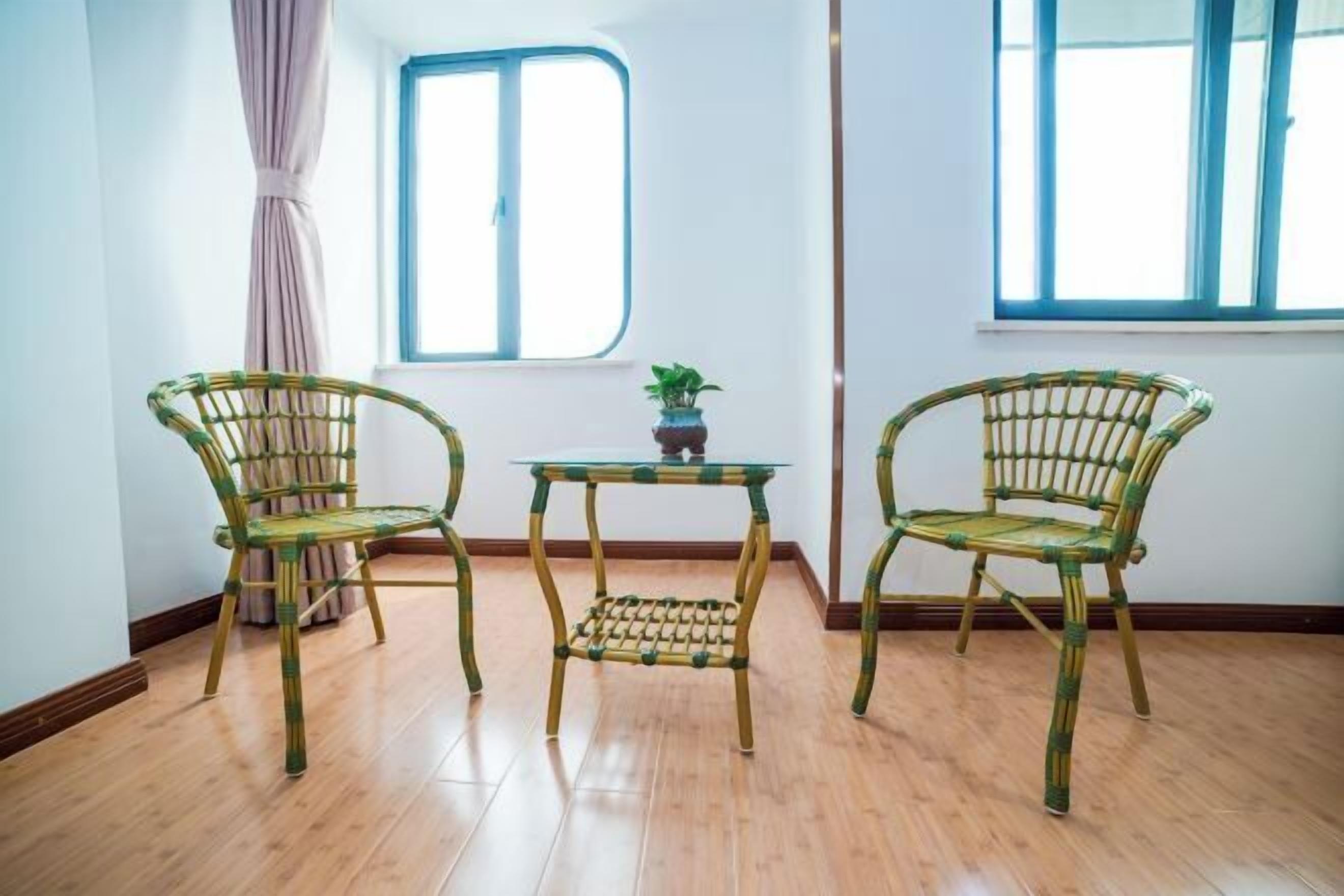 A room with two wicker chairs, a small table, and a window with curtains.