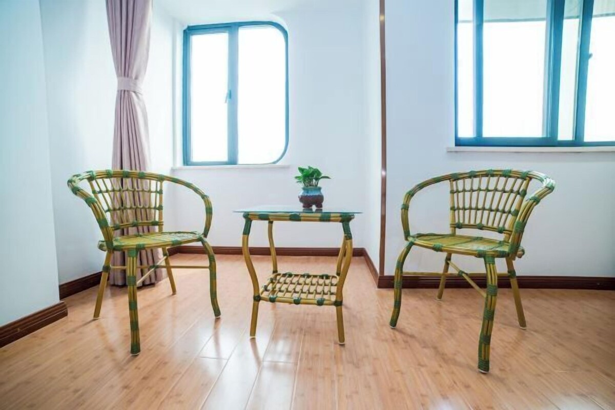 A room with two wicker chairs, a small table, and a window with curtains.