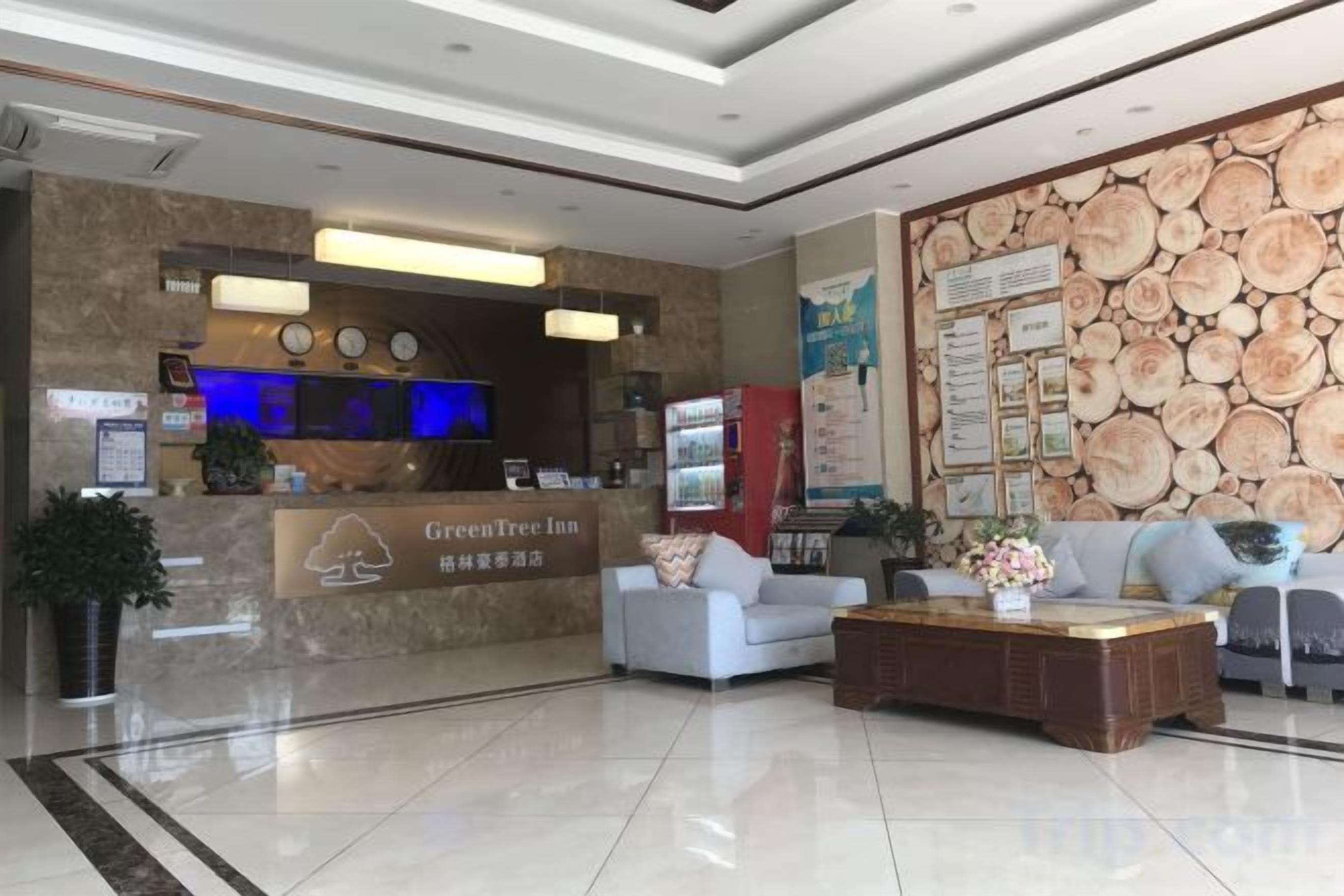 Eine Hotellobby mit einer Rezeption, einer Sitzecke und einer Wand mit Holzoptik.
