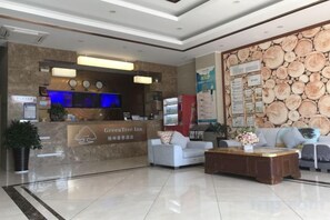 A hotel lobby with a reception desk, seating area, and a wall with a wood grain design. - GreenTree Inn (Ningbo Beilun Yintai City Huashan Road) (Ningbo)