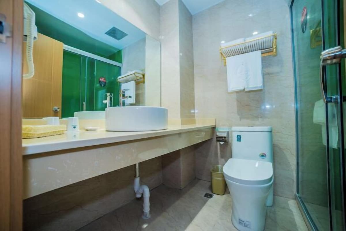 A modern bathroom with a large mirror, a sink, a toilet, and a shower area.