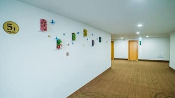 A hotel corridor with a carpeted floor, a reception desk, and a door at the end.