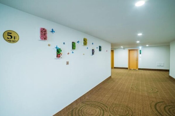 A hotel corridor with a carpeted floor, a reception desk, and a door at the end. - GreenTree Inn (Ningbo Beilun Yintai City Huashan Road) (Ningbo)