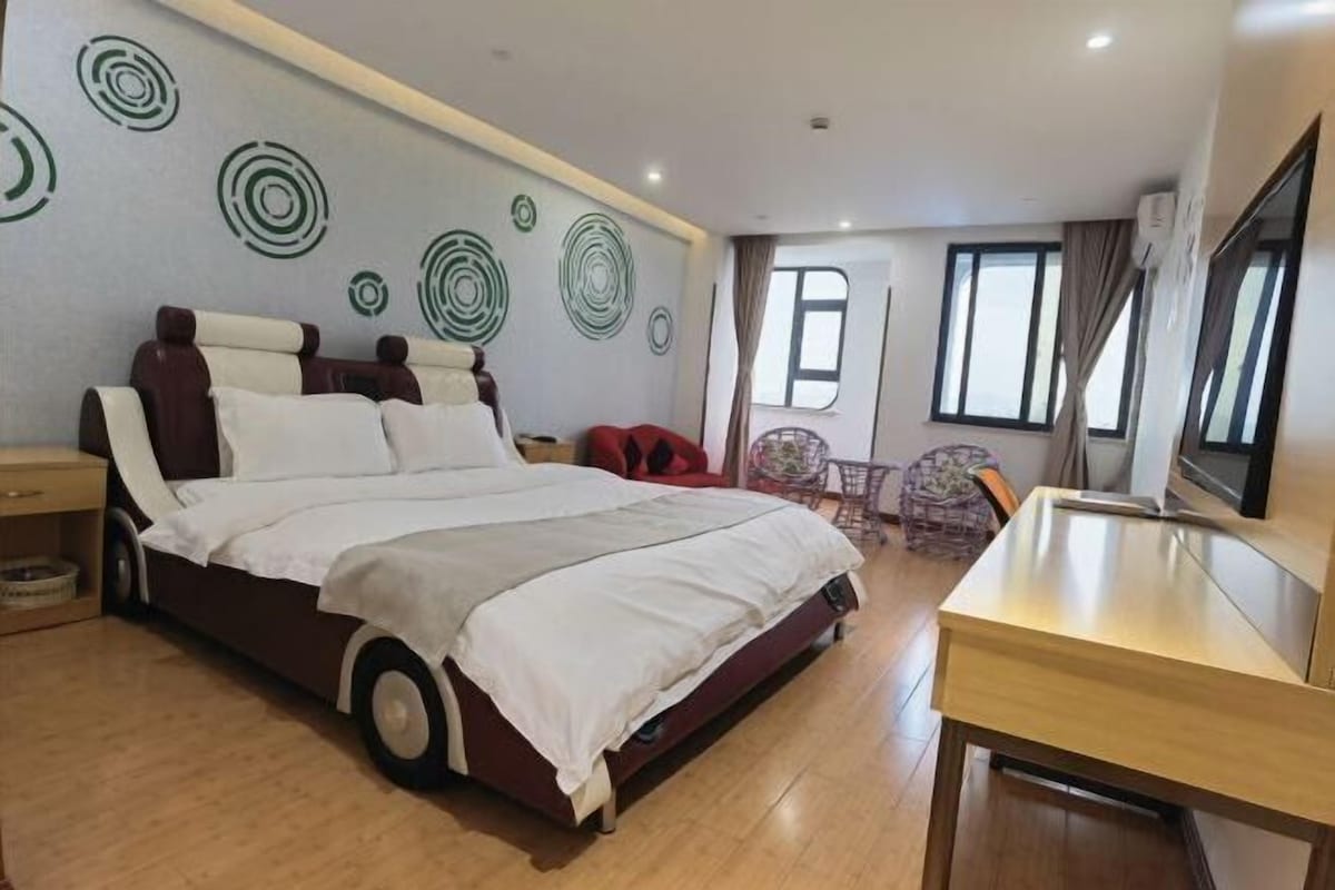 A bedroom with a large bed, a desk, and a TV.