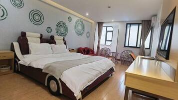 A bedroom with a large bed, a desk, and a TV.