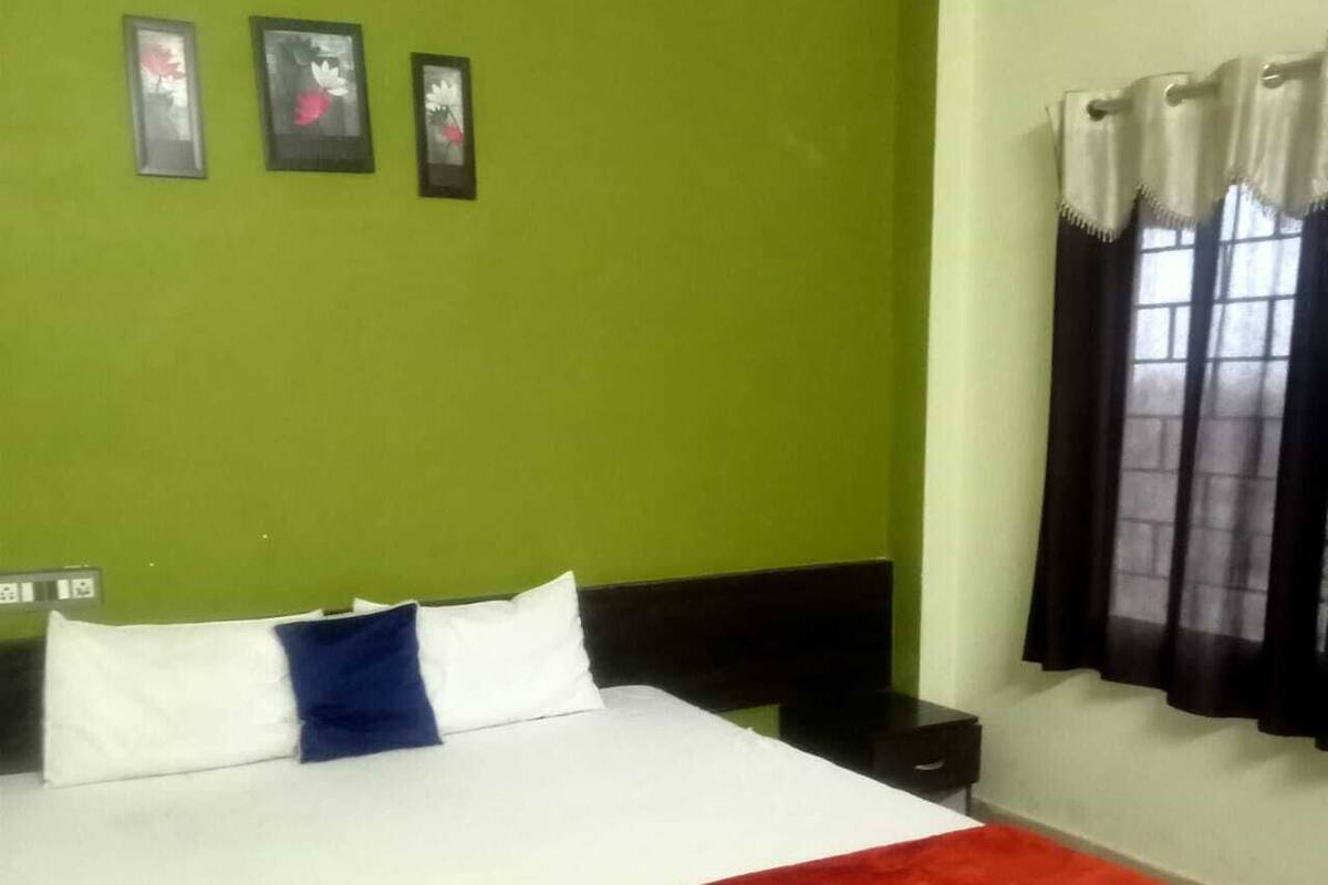 A hotel room with a bed, a nightstand, and a window with curtains.