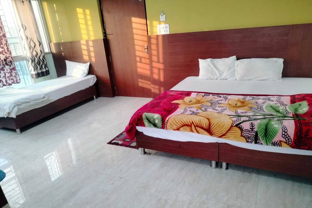 A hotel room with a large bed, a smaller bed, and a window with curtains.