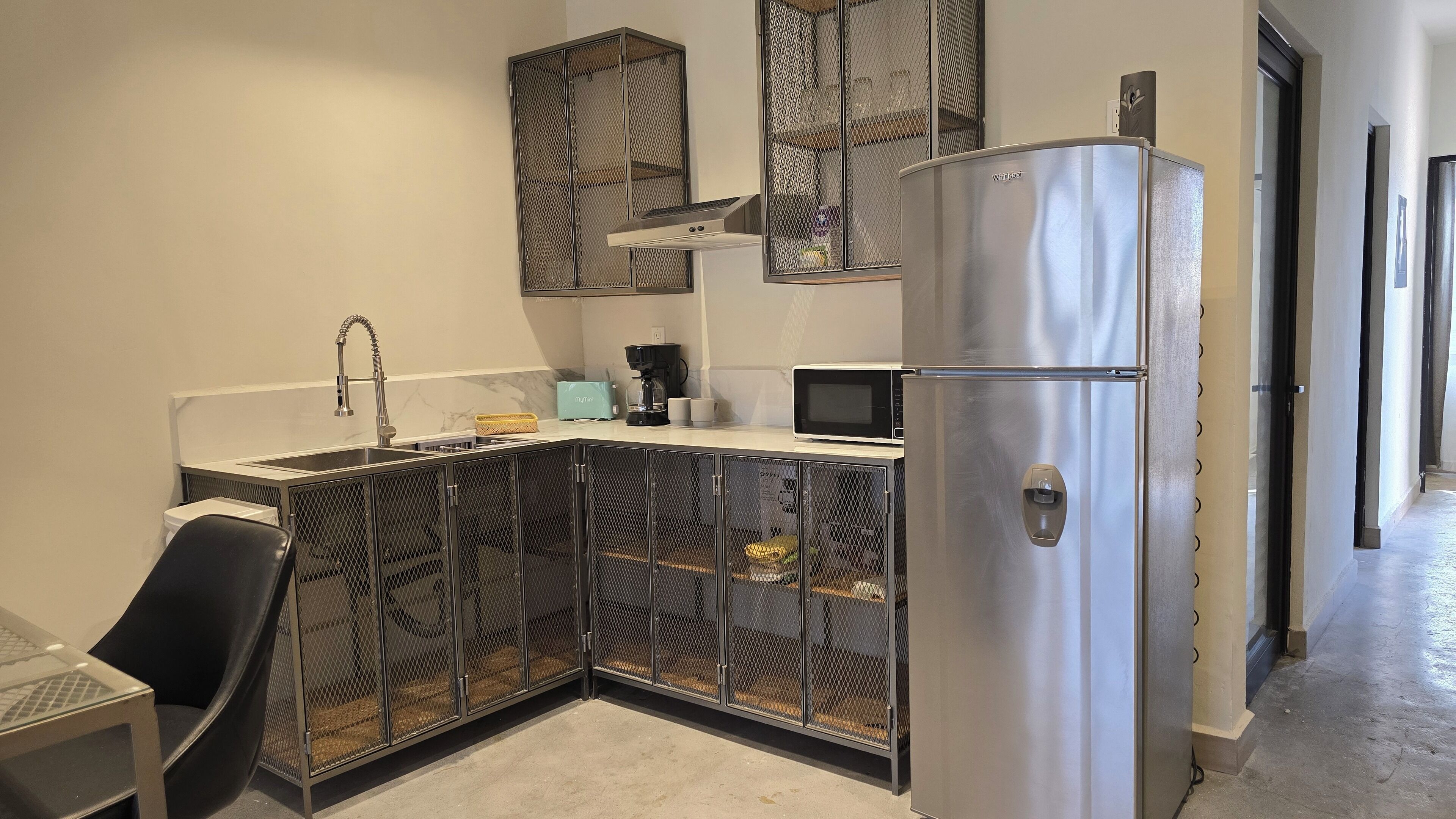 A modern kitchen with a stainless steel refrigerator, a microwave, a coffee maker, and a sink with a faucet.