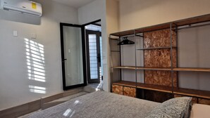 A bedroom with a bed, a wardrobe with shelves, an air conditioning unit, and a door leading to another room. - Depto Pino Blanco (Monterrey)