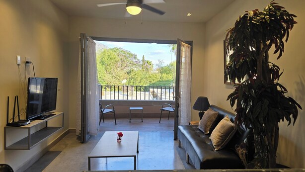 A living room with a flat-screen TV, a sofa, a coffee table, and a large potted plant. - Depto Pino Blanco (Monterrey)