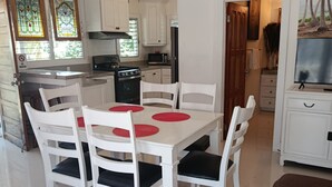 Een moderne keuken met witte kasten, een eettafel met rode placemats en een plafondventilator.