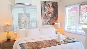 Een slaapkamer met een groot bed, een plafondventilator en een raam met zonwering.