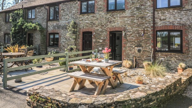 A stone building with a wooden deck and picnic table. - Tinkers Cottage (Kingsbridge)