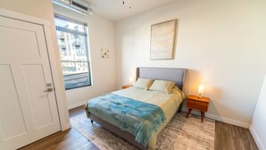 Ein Schlafzimmer mit Bett, Nachttisch, Fenster und Tür.