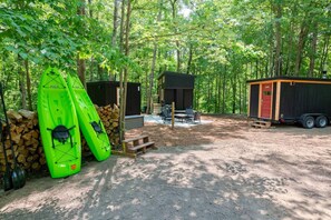 A campsite with two kayaks, a small cabin, and a trailer.