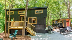A cabin with a deck, outdoor seating, and a grill area.