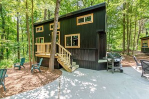 Una cabaña con terraza de madera, mobiliario exterior y zona de barbacoa.