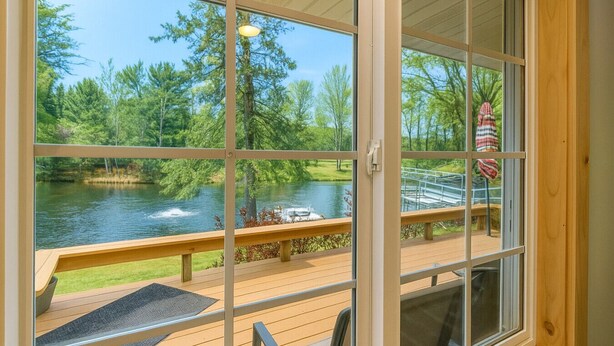 A view from a room with large windows overlooking a lake, deck, and outdoor seating area. - Lake Holcombe Waterfront Escape (Holcombe)