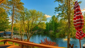 A wooden deck overlooking a lake with a view of a house and dock. - Lake Holcombe Waterfront Escape (Holcombe)