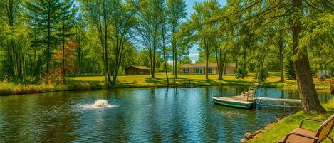 A serene lakeside setting with a dock, a boat, and a bench by the water.