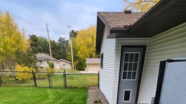 Una vasca idromassaggio in un giardino con un patio in legno e una casa sullo sfondo.