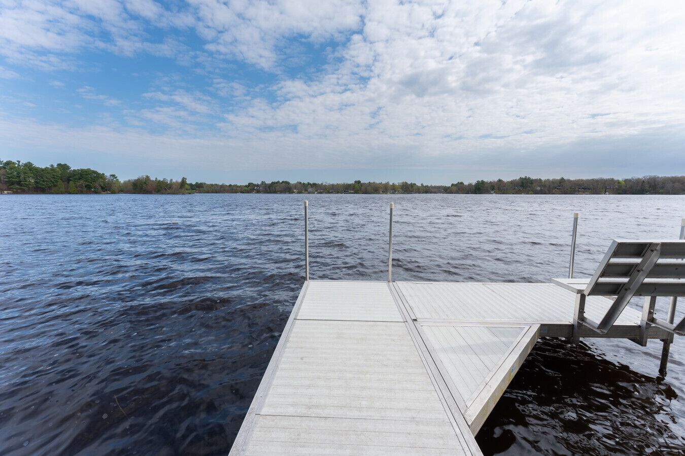 Un muelle de madera se adentra en un lago tranquilo bajo un cielo despejado.