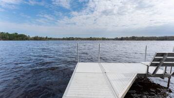 Un muelle de madera se adentra en un lago tranquilo bajo un cielo despejado.
