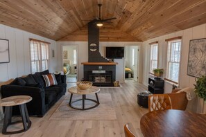 A cozy living room with a fireplace, wooden ceiling, and a comfortable seating area.