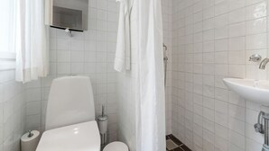 A bathroom with a toilet, a sink, and a shower area. - Small apartment in the heart of KBH (København)