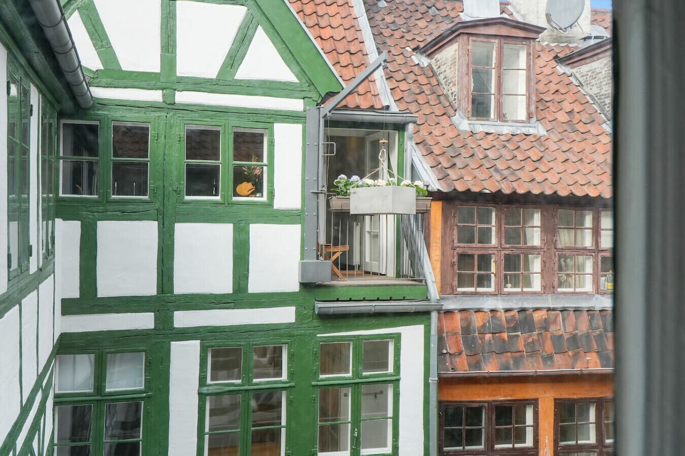 Een traditioneel vakwerkhuis met een balkon en een schotelantenne.