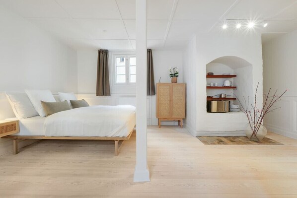 A bedroom with a wooden bed, a rattan cabinet, and a small plant.