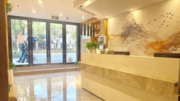 A hotel reception area with a marble counter, a large abstract mural, and a glass door entrance.