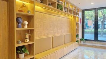 A reception area with a wooden reception desk, shelves with various items, and a large window providing a view of the outdoors.