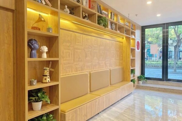 A reception area with a wooden reception desk, shelves with various items, and a large window providing a view of the outdoors. - Yuzhan (Shanghai)