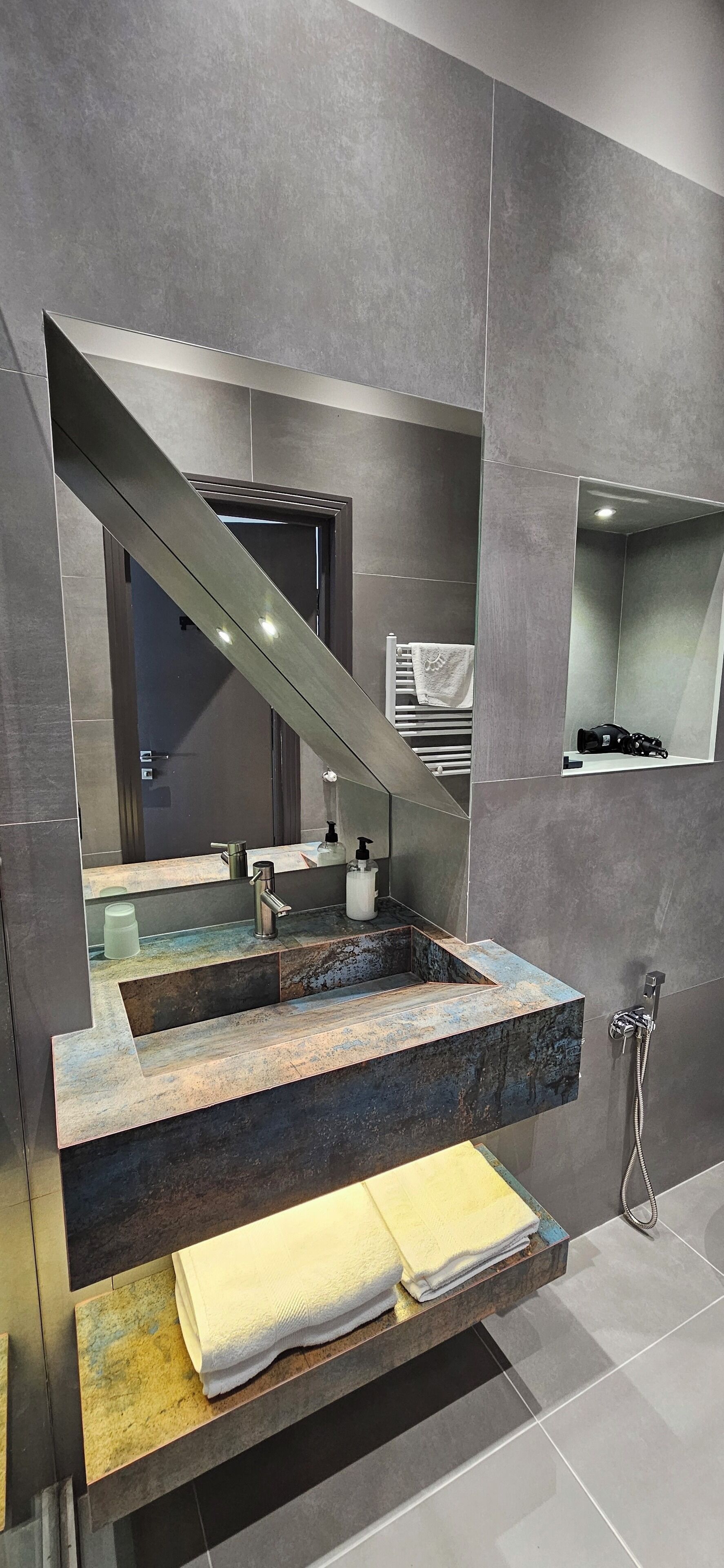 A modern bathroom with a large mirror, a built-in sink, and a shower.