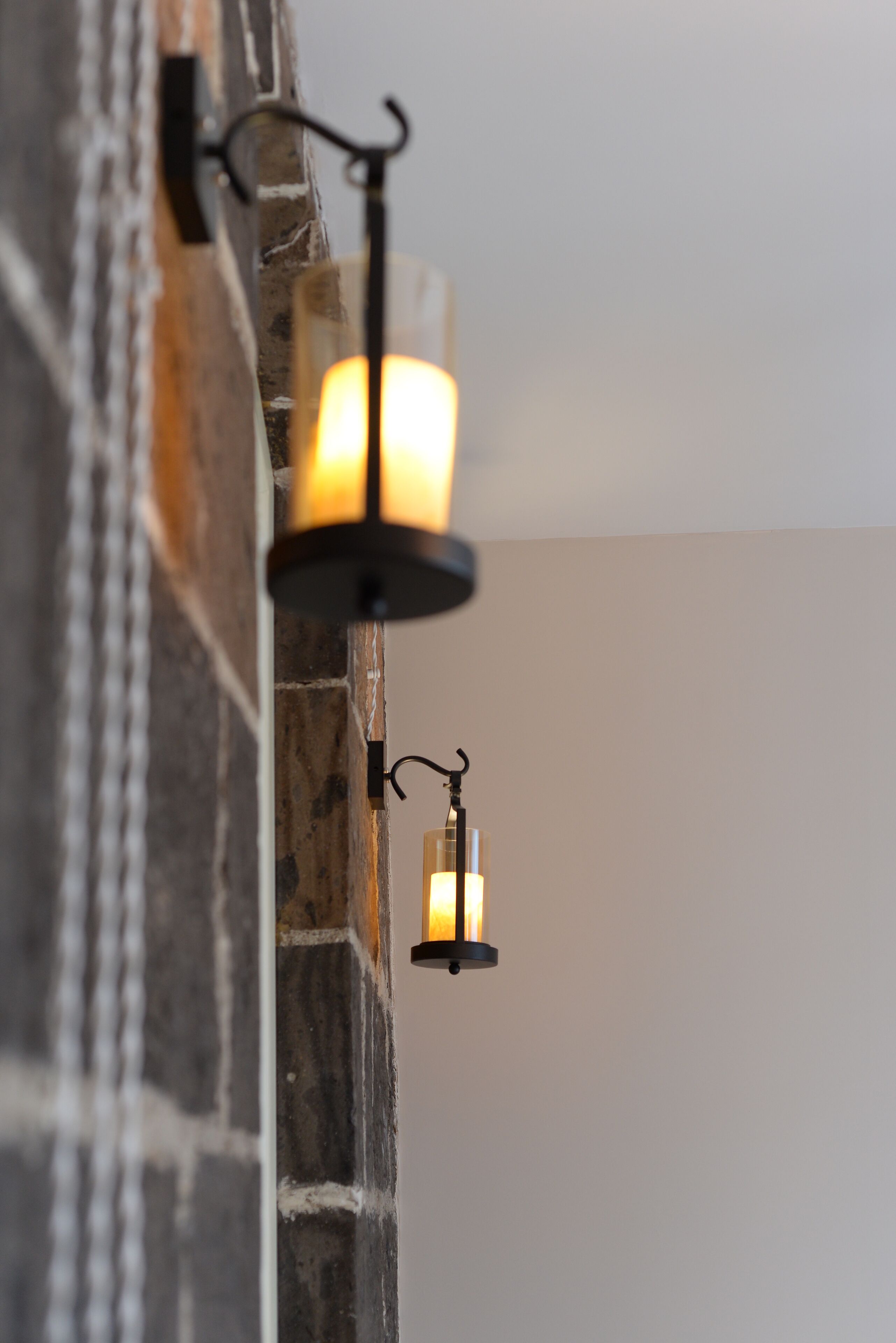 A stone wall with two wall-mounted lanterns.