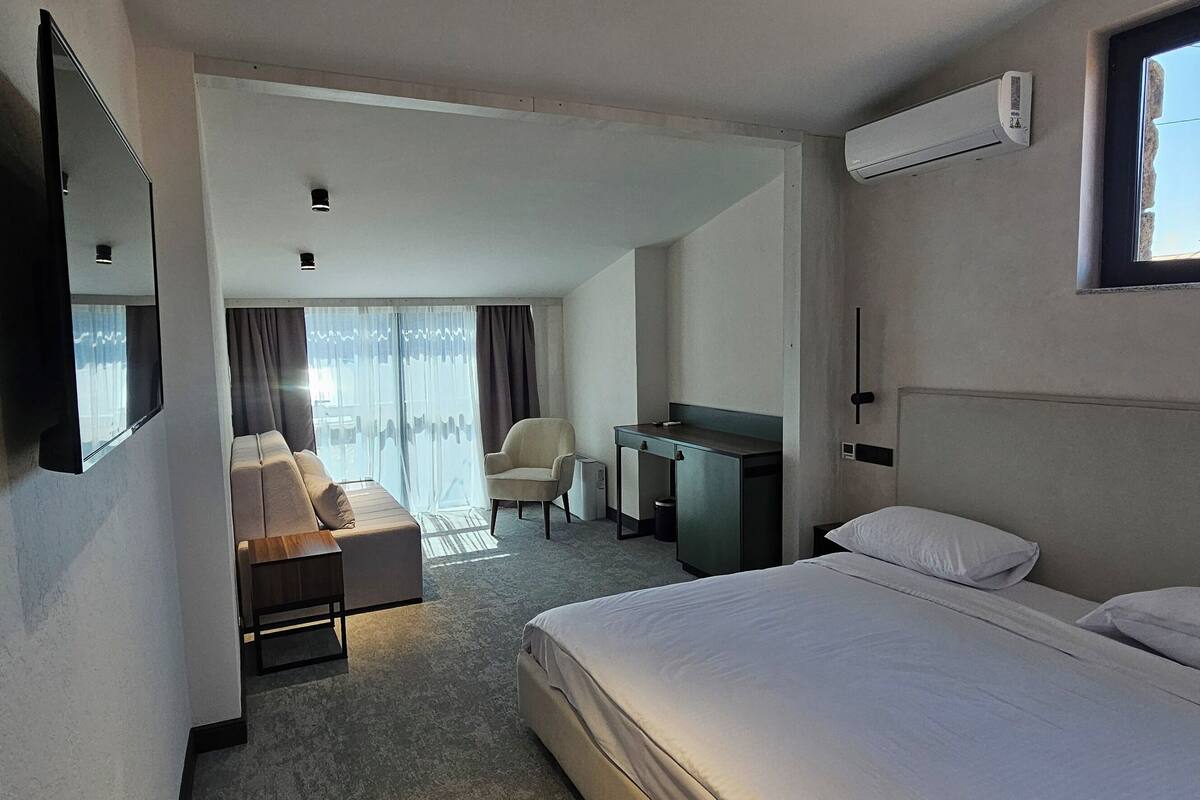 Une chambre d’hôtel avec un lit, un bureau, une chaise et un canapé.