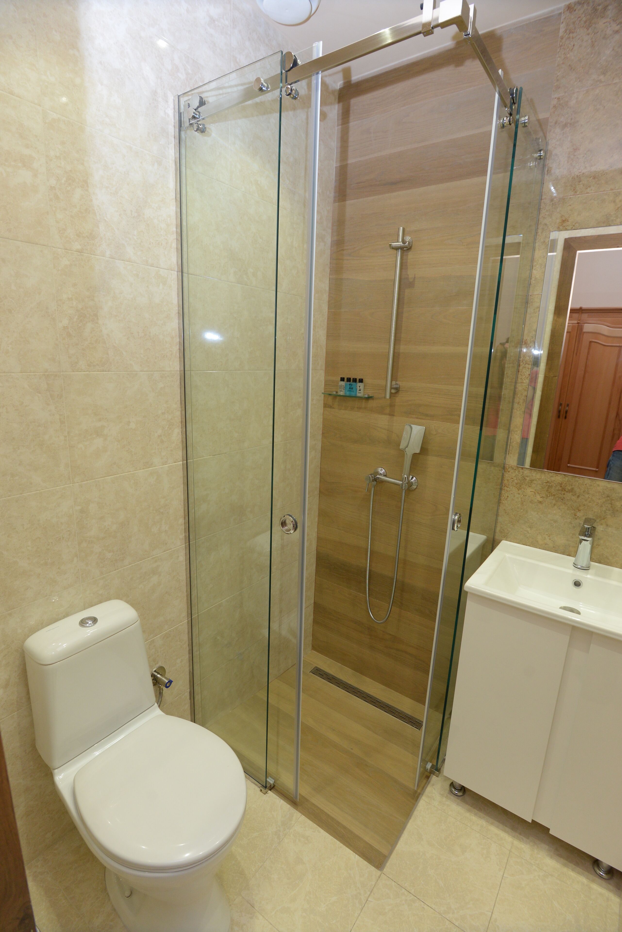 Un baño con ducha corredera de vidrio, inodoro y lavamanos.