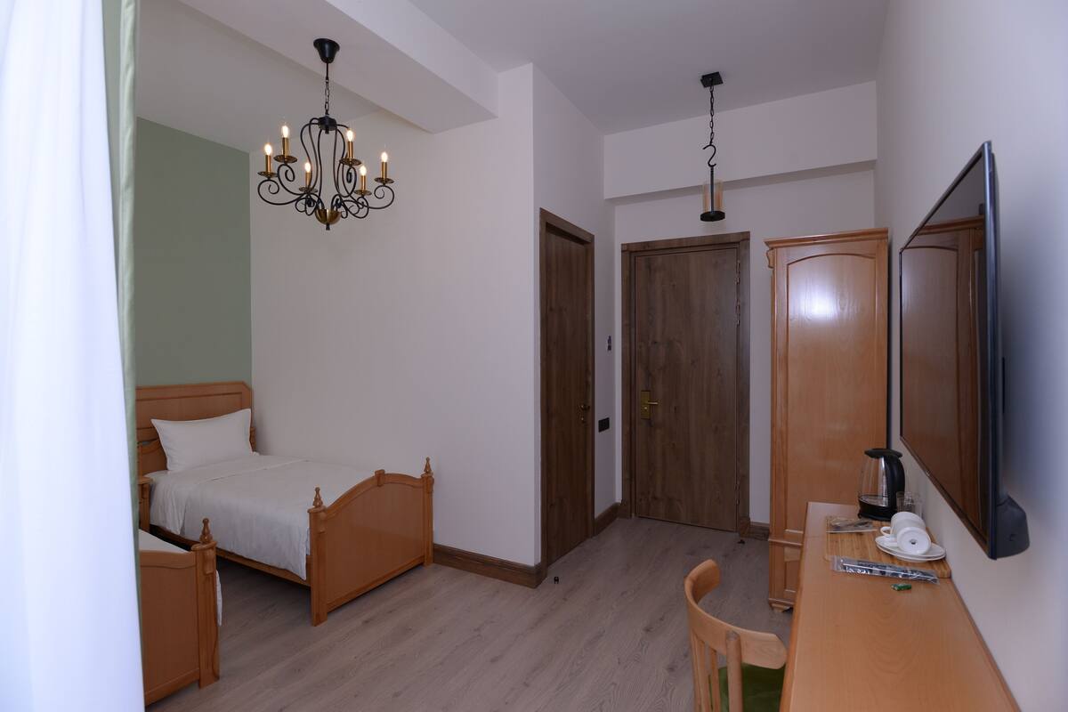 Une chambre avec un lit en bois, un bureau avec une machine à café et un miroir.