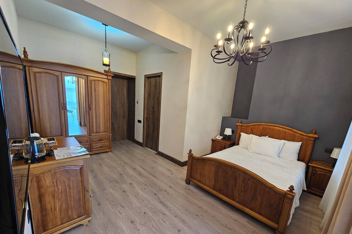 Une chambre à coucher avec un lit en bois, une table de chevet, un bureau avec une lampe et une armoire.