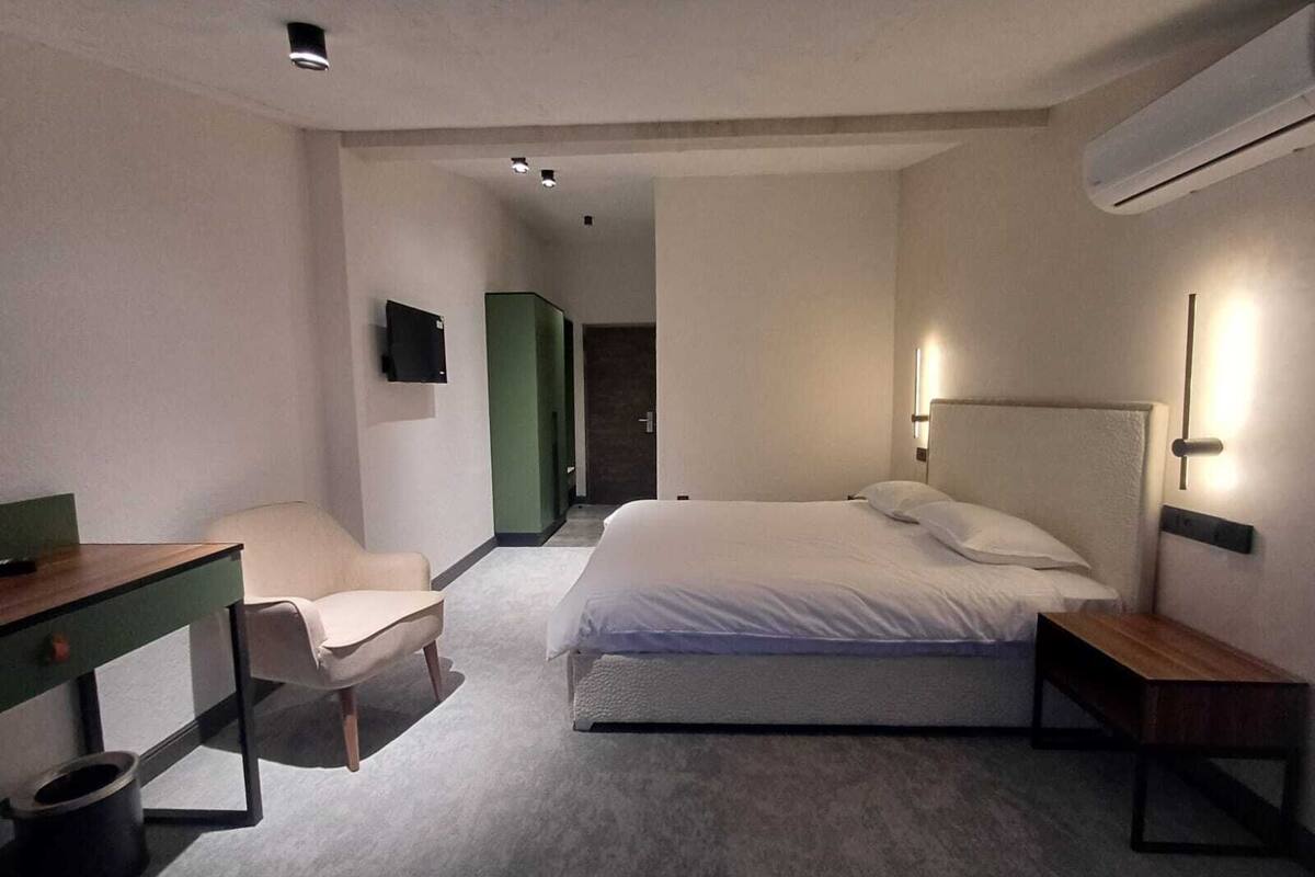 Une chambre d’hôtel avec un lit, un bureau, une chaise et un téléviseur fixé au mur.