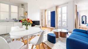 Ein modernes Wohnzimmer mit Essbereich, einem blauen Sofa und einer Küche mit weißen Schränken.