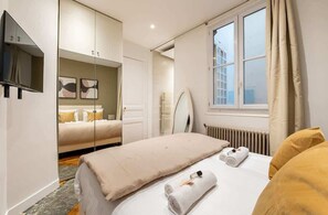 Ein Hotelzimmer mit Bett, Fernseher, Spiegel und Fenster.