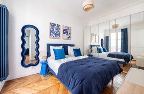 Habitación de hotel moderna con una cama grande, un espejo y obras de arte en las paredes.
