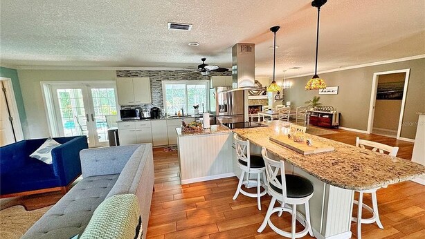A spacious living room with a large sofa and a dining area with a kitchen in the background. - 2Bd 2Ba Get Away In The Prestigious Meadows Community! Golf, Tennis, and More! (Sarasota)