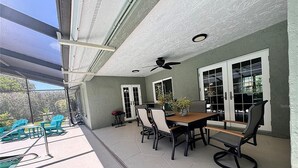 An outdoor patio with a dining table and chairs, a ceiling fan, and a view of the backyard. - 2Bd 2Ba Get Away In The Prestigious Meadows Community! Golf, Tennis, and More! (Sarasota)