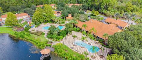 A resort with multiple swimming pools, a lake, and lush greenery.