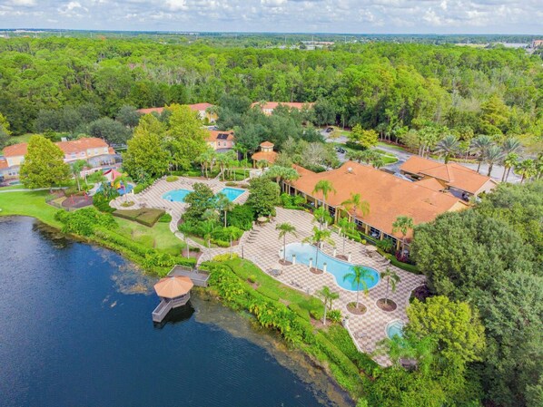 A resort with multiple swimming pools, a lake, and lush greenery.